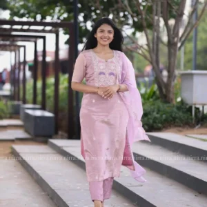 Smiling woman in a light pink silk kurta set with embroidered dupatta outdoors