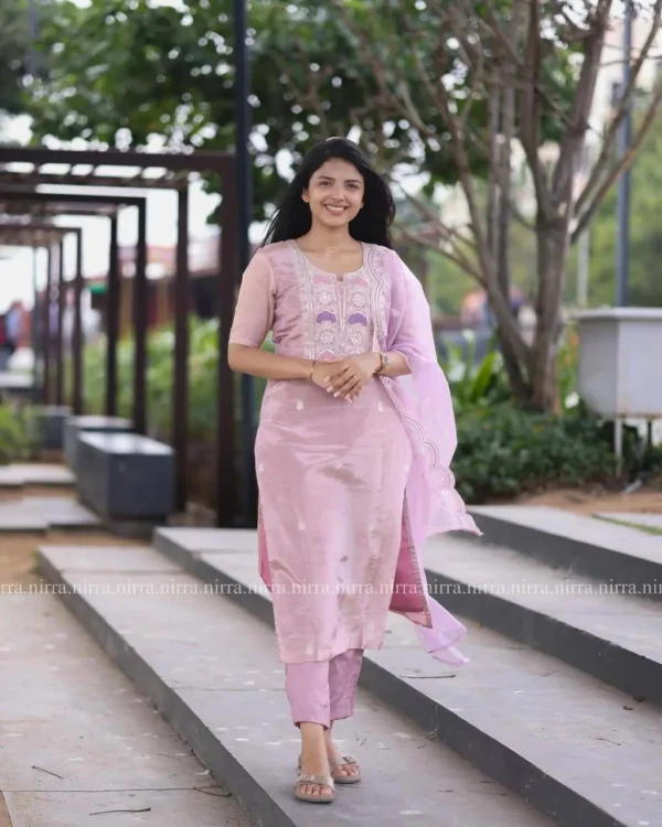 Smiling woman in a light pink silk kurta set with embroidered dupatta outdoors